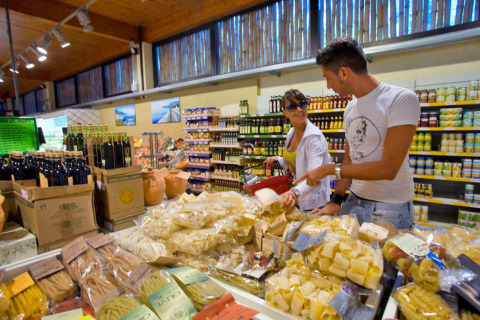 Pareja comprando pasta y aceite de oliva en un supermercado en hu Park Albatros Village, Toscana, Italia.