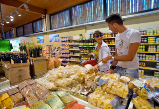 Pareja comprando pasta y aceite de oliva en un supermercado en hu Park Albatros Village, Toscana, Italia.