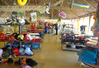 Winkel in hu Park Albatros Village te Toscane, Italië met kledij, petten en zwemspullen onder rieten dak.