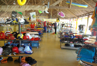 Butik i hu Park Albatros Village, Toscana, Italien med tøj, hatte og badetøj under stråtag.