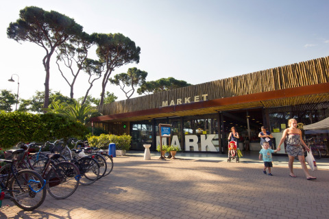 Foto del mercado en hu Park Albatros Village, un parque vacacional en la Toscana, Italia, con familias y bicis.