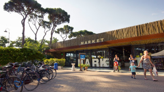 Foto del mercado en hu Park Albatros Village, un parque vacacional en la Toscana, Italia, con familias y bicis.