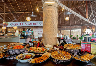 Buffet table with different dishes and sauces under thatched roof at hu Park Albatros Village, Tuscany, Italy.