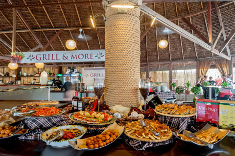 Tavolo buffet con vari piatti e salse sotto tetto in paglia a hu Park Albatros Village, Toscana, Italia.