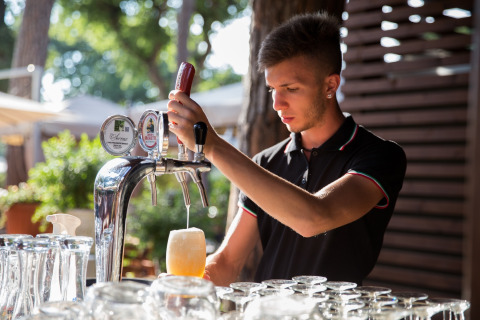 En bartender tapper øl fra fadølshanerne i hu Park Albatros Village, en feriepark i Toscana, Italien.