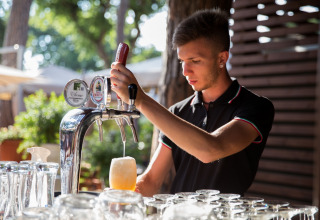 Un barman sert une bière pression au hu Park Albatros Village, un village vacances en Toscane, Italie.