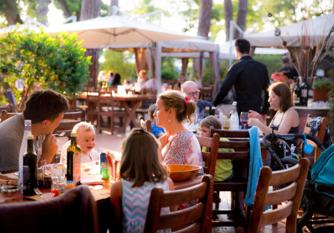 Families dining outdoors at a restaurant in hu Park Albatros Village, Tuscany, Italy, enjoying the evening.