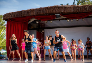 Personas disfrutan de una clase de baile animada en el escenario del hu Park Albatros Village, Toscana, Italia.