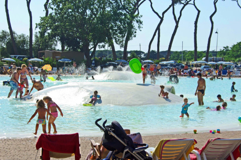 Bambini e famiglie giocano in una piscina bassa con fontane d'acqua al hu Park Albatros Village, Toscana, Italia.