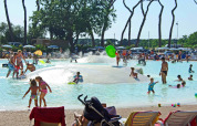 Niños y familias disfrutan en una piscina baja con fuentes de agua en hu Park Albatros Village, Toscana, Italia.