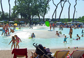 Children and families playing in a shallow pool with water fountains at hu Park Albatros Village, Tuscany, Italy.