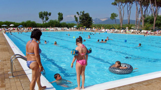 Piscina al aire libre llena de gente en hu Park Albatros Village, Toscana, Italia, día soleado de verano.