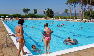 Piscina al aire libre llena de gente en hu Park Albatros Village, Toscana, Italia, día soleado de verano.