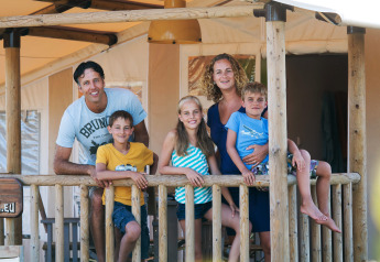 Familia disfruta en la terraza de SunLodge Jungle en Camping Village Cavallino, Italia.