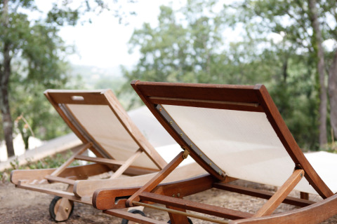 Due lettini in legno su terreno naturale circondati da alberi al SunLodge Jungle in Italia.