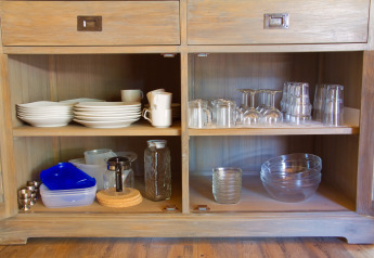 Armario abierto con platos, tazas, vasos y cuencos en SunLodge Jungle en Camping Village Cavallino, Italia.