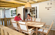 Pareja tomando café en la terraza de SunLodge Redwood en Camping Village Cavallino, Italia, bajo pérgola.