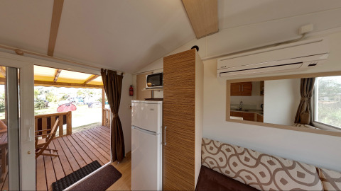 Binnenkant van SunLodge Redwood bij Camping Village Cavallino in Italië met terras, koelkast en keukenhoek.