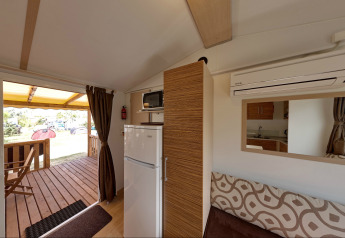 Intérieur de la SunLodge Redwood au Camping Village Cavallino, Italie, avec terrasse, frigo et kitchenette.