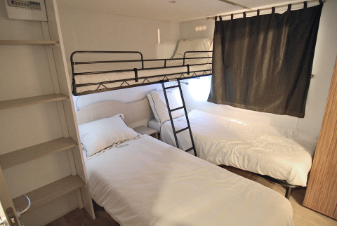 Chambre à SunLodge Redwood, Camping Village Cavallino en Italie, avec deux lits simples et un lit superposé.