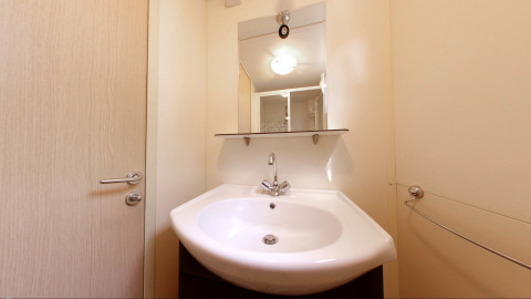 Moderne badkamer met witte lavabo, spiegel en rek in SunLodge Redwood in Camping Village Cavallino, Italië.