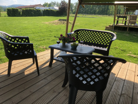 Terras met zwarte tuinstoelen, wijn en bloemen bij Safari tent Camping de Regenboog, Tsjechië