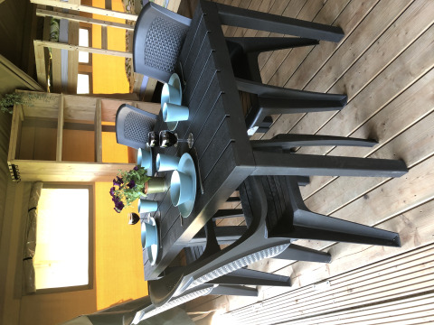 Black plastic dining table with blue dishes and flowers inside a safari tent at Camping de Regenboog, Czech Republic.