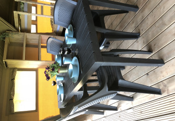 Ein schwarzer Esstisch mit blauem Geschirr und Blumen in einem Safarizelt auf Camping de Regenboog in Tschechien.