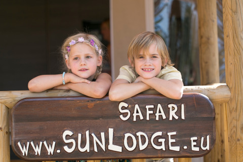 Twee kinderen leunen op een SunLodge Safari-bord in Camping Village Cavallino (Suncamp), Italië.