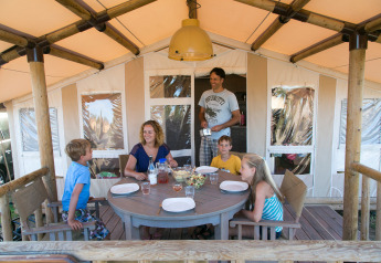 Family dining together on the terrace of a SunLodge Safari at Camping Village Cavallino in Italy.