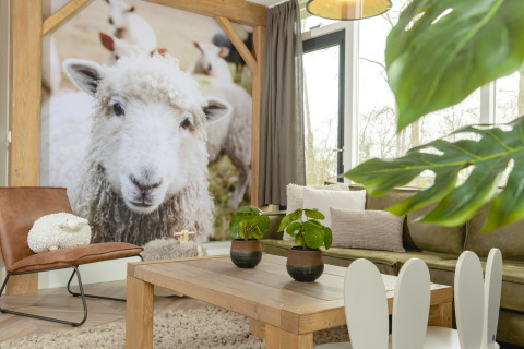Lyst og moderne opholdsstue i Baby & children bungalow på Holiday Park Mölke, dekoreret med fåreplakat.