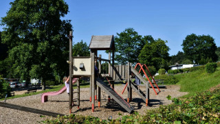 Parque infantil en un complejo de glamping, niños jugando en el tobogán y columpios rodeados de naturaleza.