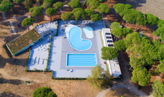 Vista aérea de la zona de piscinas en Camping Village Roma Capitol, rodeada de árboles en la Toscana, Italia.