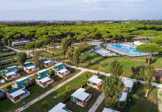 Aerial view of Camping Village Roma Capitol featuring bungalows, a large pool, and pine forest in Tuscany.