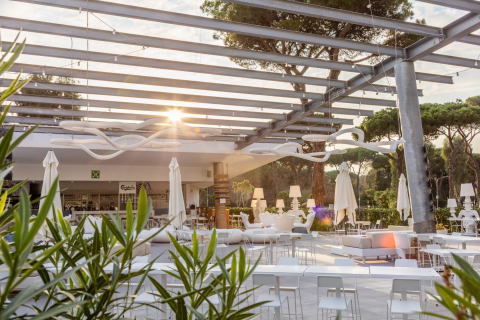 Area lounge all'aperto con arredi moderni bianchi al Camping Village Roma Capitol in Toscana, Italia, al tramonto.
