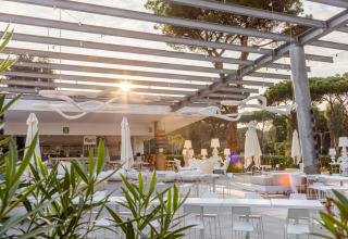 Outdoor lounge area with modern white furniture and sunlight at Camping Village Roma Capitol in Tuscany, Italy.
