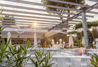 Espace lounge extérieur moderne avec mobilier blanc au Camping Village Roma Capitol, en Toscane, Italie, au soleil.