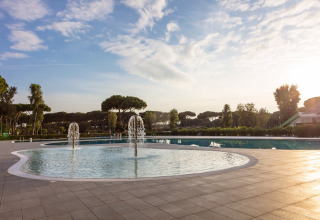 Piscina con fontane d'acqua e alberi sullo sfondo al Camping Village Roma Capitol, Toscana, Italia.