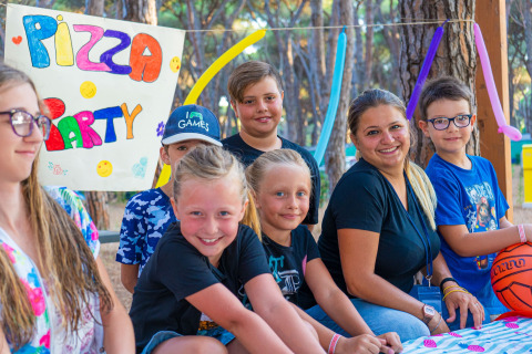 Niños y adultos felices disfrutan de una fiesta de pizza en Camping Village Roma Capitol, Toscana, Italia.