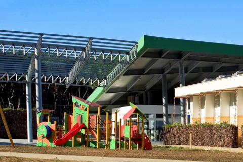 Parco giochi e edifici moderni al sole presso il Camping Village Roma Capitol in Toscana, Italia.