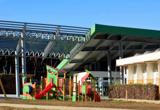 Parco giochi e edifici moderni al sole presso il Camping Village Roma Capitol in Toscana, Italia.