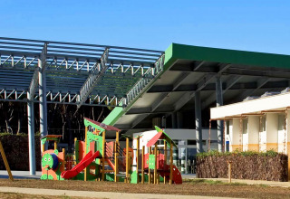 Legeplads og bygninger i solskin på Camping Village Roma Capitol feriepark i Toscana, Italien.