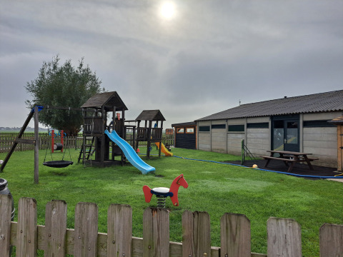 Parco giochi con scivoli e altalene sull'erba al Camping de Speld, villaggio vacanze in Olanda Meridionale, Paesi Bassi.