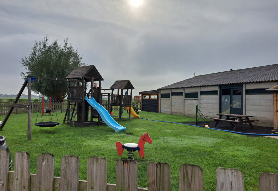Spielplatz mit Rutschen und Schaukeln auf Gras bei Camping de Speld, einem Ferienpark in Südholland, Niederlande.