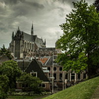 Blick auf eine Kirche und traditionelle Häuser in grüner Umgebung bei bewölktem Himmel in Nieuwkoop, Niederlande.