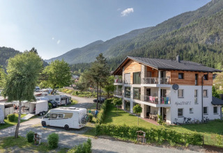 Feriebillede fra en feriepark med campingvogne, bjergudsigt og moderne glampingindkvartering.