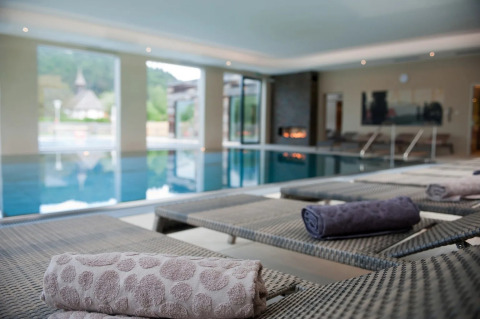 Zona de piscina cubierta con tumbonas y toallas enrolladas en un parque de vacaciones glamping.