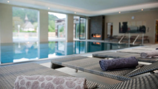 Luxe overdekt zwembad met ligstoelen en opgerolde handdoeken in een glamping vakantiepark.