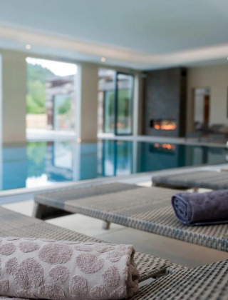 Luxe overdekt zwembad met ligstoelen en opgerolde handdoeken in een glamping vakantiepark.