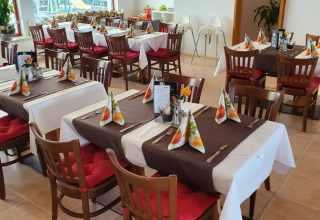 Cozy restaurant with red cushions, festive napkins on tables and window view to playground outside.